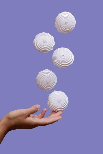 Marshmallow Drijvend Lucht Onder Hand Tegen Een Paarse Achtergrond Stockafbeelding