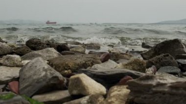Ufukta seyreden bir gemi ile odak noktasındaki kayanın yavaş çekim görüntüsü