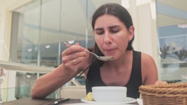 Genç bir kadın şehirdeki restoranda mısır çorbası içiyor.
