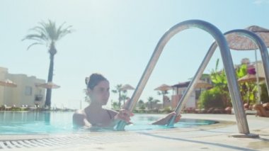 Tropik bir kaplıcada yüzme havuzundan çıkan sportif bir kadın.