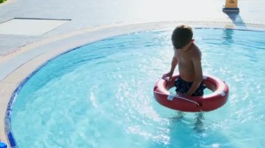 Hayat şamandıralı çocuk tropikal tatil köyünde yüzme havuzunda oynuyor.