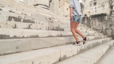 Sandaletli bir kadın, güneşli bir günde antik şehrin merdivenlerinden çıkar. Yavaş çekimde, turist zirveye tırmanır. Dinlen, seyahat et, tırman. Güzel görüntüler. döşeme