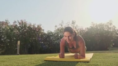 Spor kıyafetli kadın dışarıda yoga pozu veriyor. Parkta esneme hareketleri yapan atletik kız. Spor salonundaki kadın yeşil çimenler üzerinde yoga egzersizleri yapıyor. Açık havada spor yapan bir kız. Yavaş çekim
