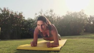 Spor kıyafetli kadın dışarıda yoga pozu veriyor. Parkta esneme hareketleri yapan atletik kız. Spor salonundaki kadın yeşil çimenler üzerinde yoga egzersizleri yapıyor. Açık havada spor yapan bir kız. Yavaş çekim