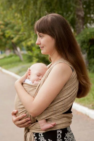 Newborn baby sleeping in sling, in embrace of mother. — Stock Photo, Image