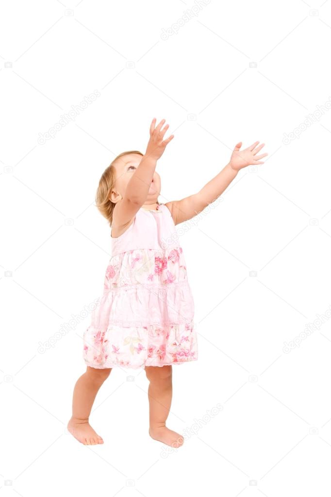 Pretty baby girl standing and holding hands in the air, reaching for something. Isolated on white background with clipping path