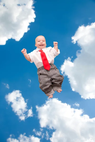 Tiny newborn baby smiling flying up into the sky and clouds. — Stock Photo, Image