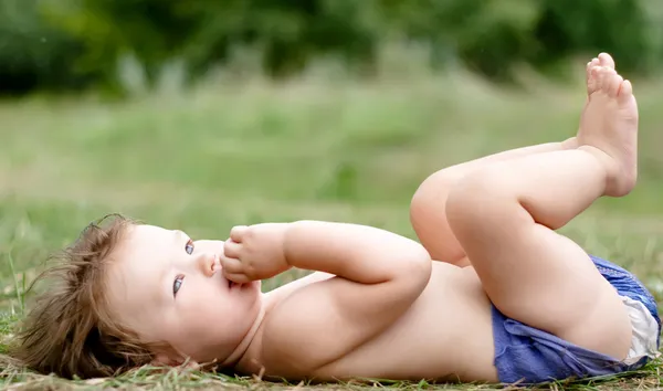 Baby in diapers lying on his back on the grass — Stock Photo, Image