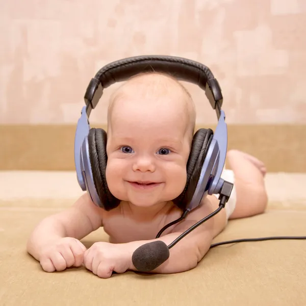 Menino recém-nascido com olhos azuis sorrindo usando um fone de ouvido . — Fotografia de Stock