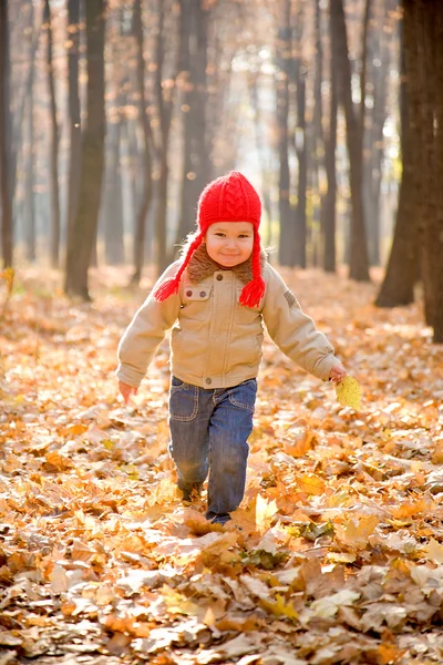 Kind läuft und lächelt im herbstlichen Wald — Stockfoto