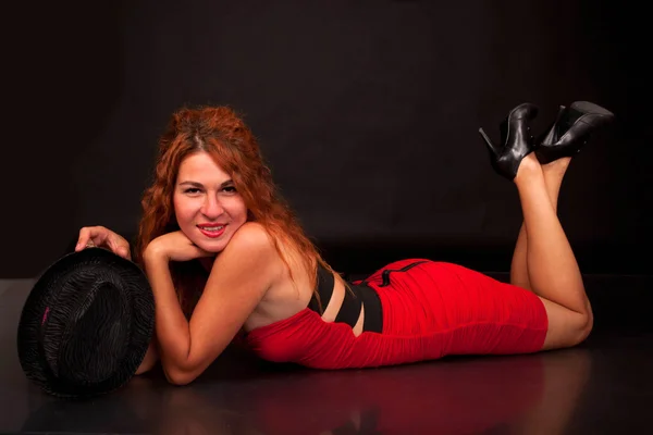 Sexy young red-haired woman lying on black — Stock Photo, Image