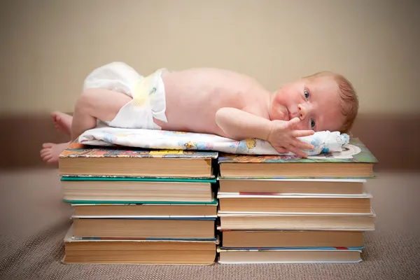 Bebê deitado em uma pilha de livro — Fotografia de Stock