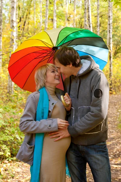 Happy pregnant woman and man walking in autumn forest — Stock Photo, Image