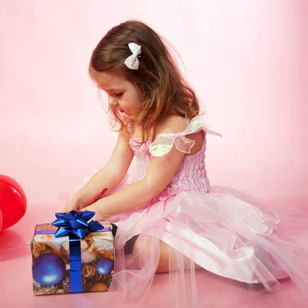 Criança vestindo vestido rosa regozijando e olhando presentes de Natal — Fotografia de Stock