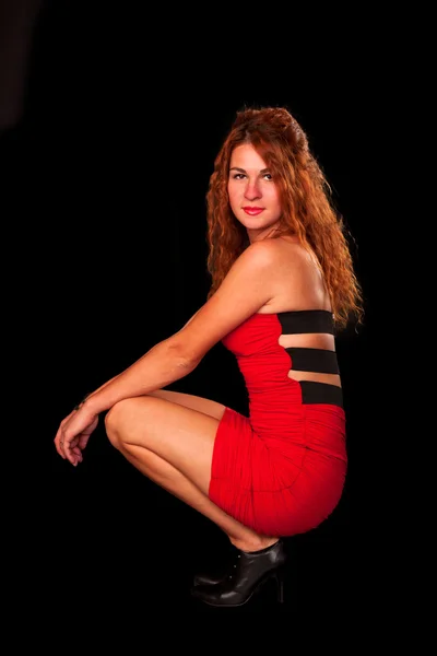 Sexy giovane donna dai capelli rossi in possesso di pistola isolato su sfondo nero — Foto Stock