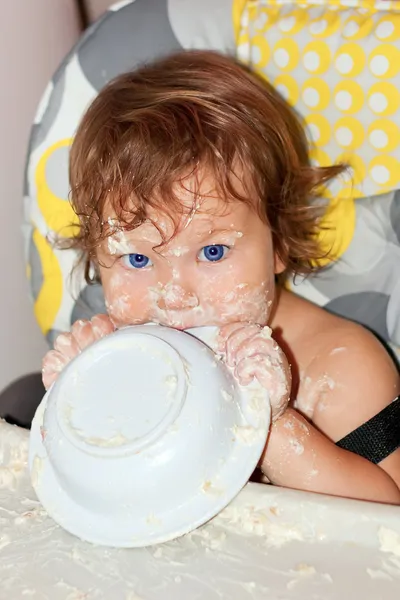 Bebé comiendo yogur y la cara sucia, las manos y todo alrededor —  Fotos de Stock