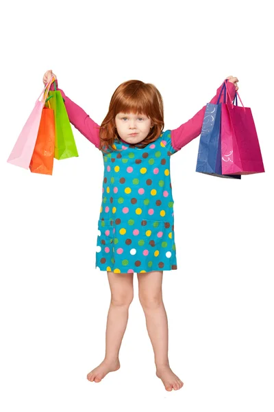 Pequena menina ruiva bonita com sacos de compras — Fotografia de Stock