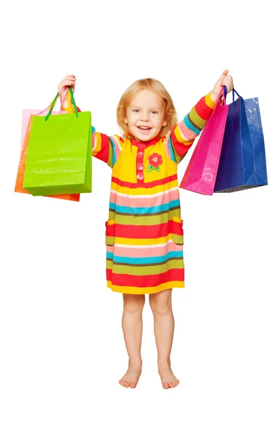 Pequeña chica rubia hermosa con bolsas de compras Imagen de stock