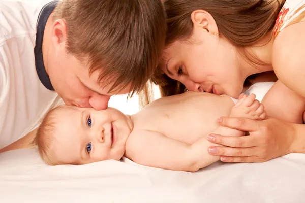 幸福的家庭观念。亲吻宝宝的父母 免版税图库图片