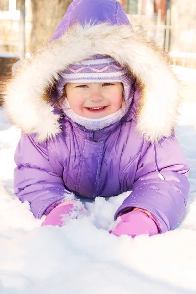 Happy smiling baby lying in the snow — Stock Photo, Image