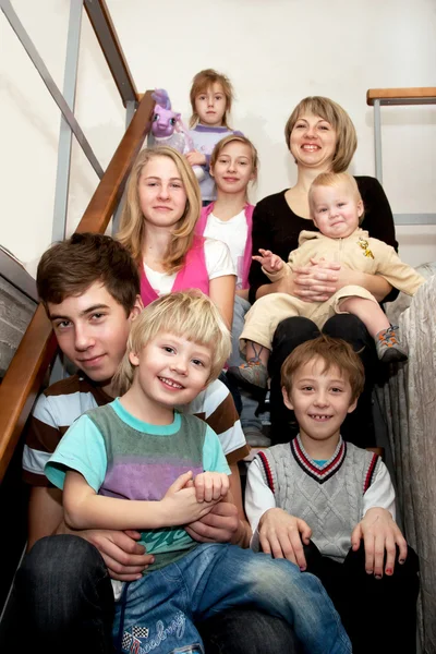 Grande família feliz sentado nas escadas em casa . — Fotografia de Stock