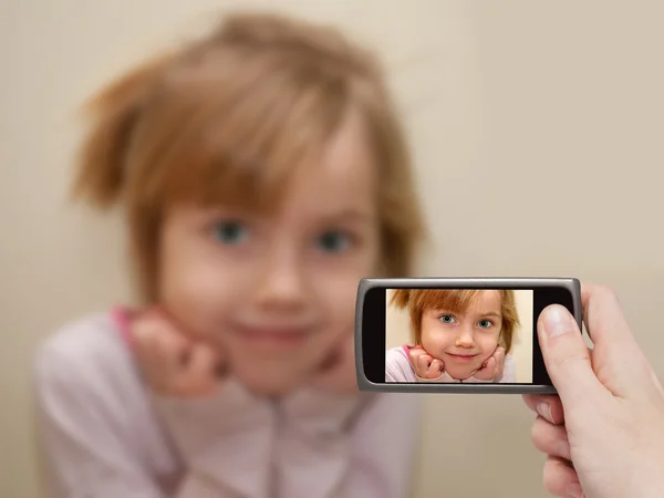 La mano del hombre haciendo la foto de una niña con un teléfono móvil . — Foto de Stock
