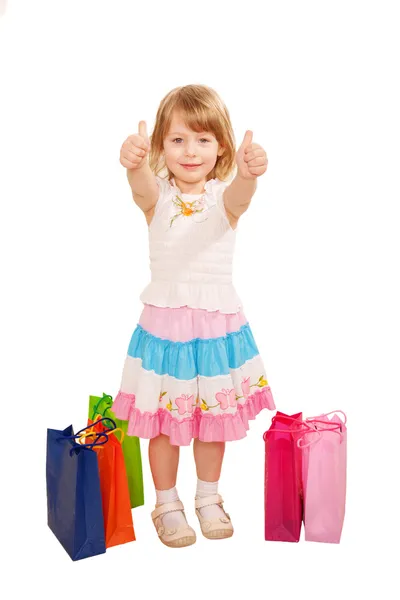 Little girl buyer with shopping bags showing a thumbs up or OK s — Stock Photo, Image