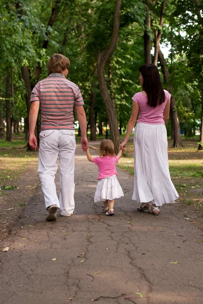 Uma jovem família, pai, mãe e filha criança andando em t — Fotografia de Stock