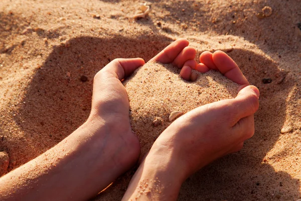 Två händer utgör hjärtat av sand. — Stockfoto