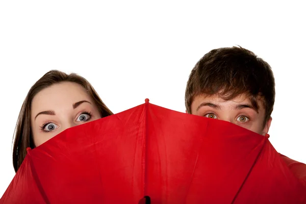 Teenager, ein Junge und ein Mädchen, lugen nach dem roten Regenschirm. — Stockfoto