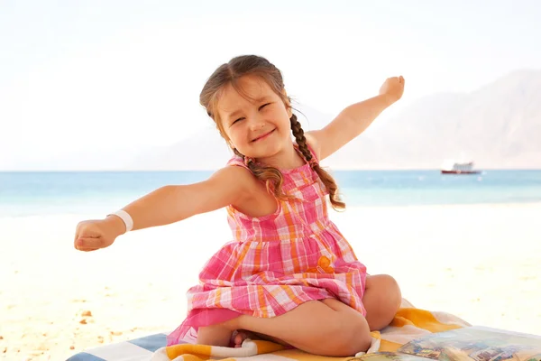 快乐的小女孩坐在休息区的海滩上 — 图库照片