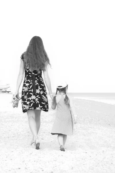 Madre e figlia che camminano sulla spiaggia. Bianco e nero . — Foto Stock