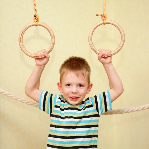 Criança brincando de esportes em anéis de ginástica — Fotografia de Stock