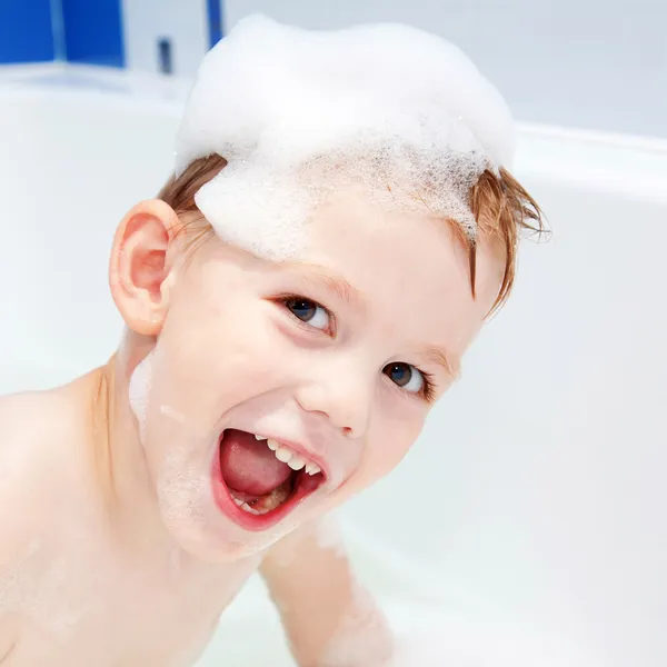 Zabawne dziecko z cap pianki na głowie w łazience. — Zdjęcie stockowe