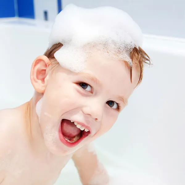 Grappige kind met dop van schuimrubber op hoofd in badkamer. — Stockfoto