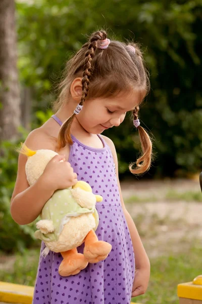 Dziewczynka z warkoczykami opieki zabawka. — Zdjęcie stockowe