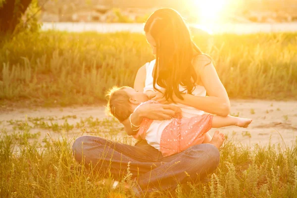 Moeder borst voeden van de baby in het zonlicht bij zonsondergang — Stockfoto