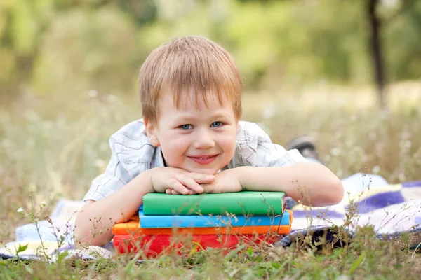 Αστείος αγόρι και ένα βιβλίο σε εξωτερικούς χώρους. επιστροφή στο σχολείο. — Φωτογραφία Αρχείου