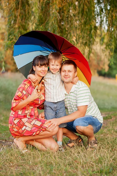 Отец, мать и сын с разноцветным зонтиком . — стоковое фото