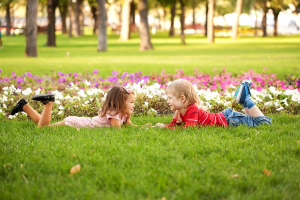 Kleine jongen en meisje liggen op het gras — Stockfoto