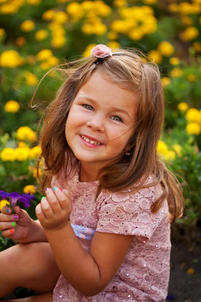 Glücklich schönes kleines Mädchen mit Blumen. — Stockfoto