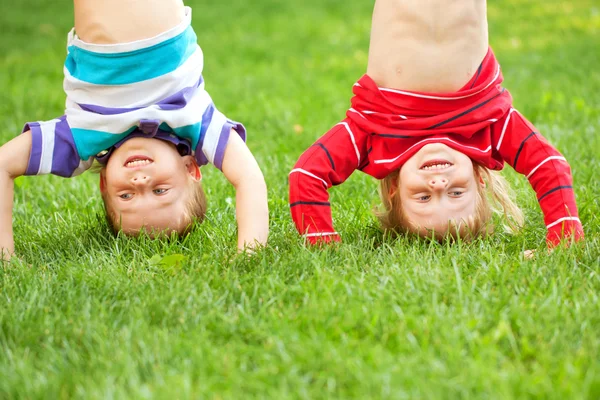 Happy children standing upside down on grass. — Stock Photo, Image