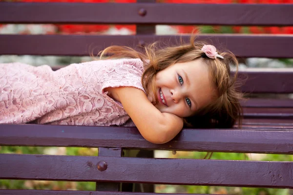 Menina deitada no banco do parque . — Fotografia de Stock