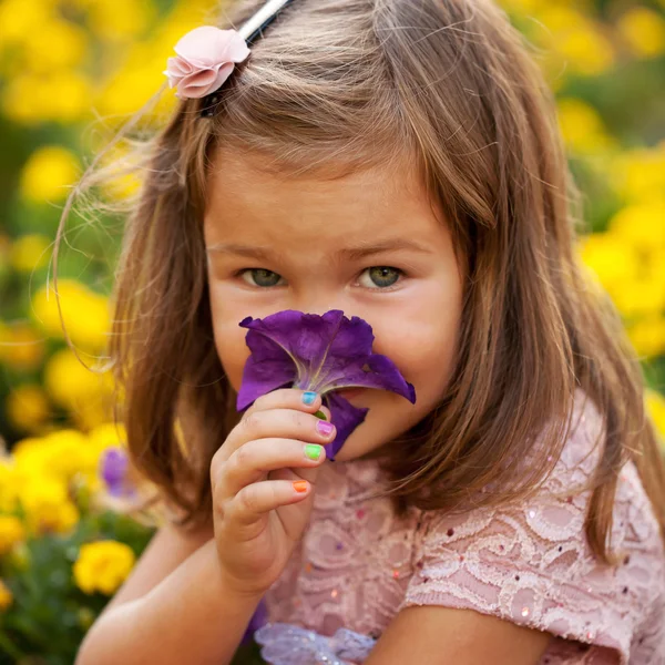 Little girl smelling flower close up. — Stock Photo, Image