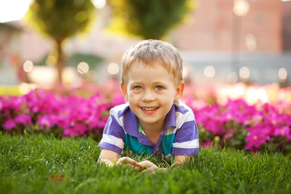 Mały chłopiec pachnący kwiat bliska. — Zdjęcie stockowe