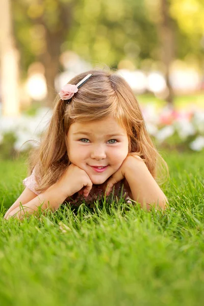 Happy beautiful little girl lying on the grass Royalty Free Stock Photos