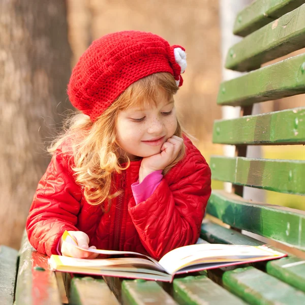 Malá holčička, čtení knihy v parku. — Stock fotografie