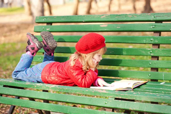 Kleines Mädchen liest im Park ein Buch. — Stockfoto