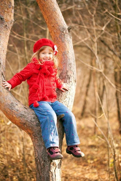 Legrační malá holka sedí na stromě — Stock fotografie