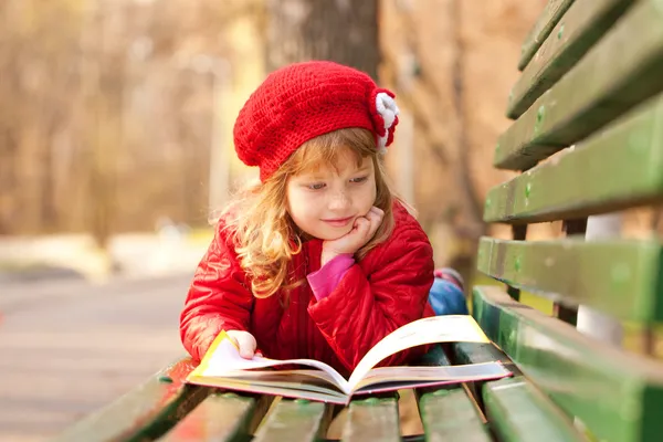 Feliz niña sonriente leyendo interesante libro — Foto de Stock